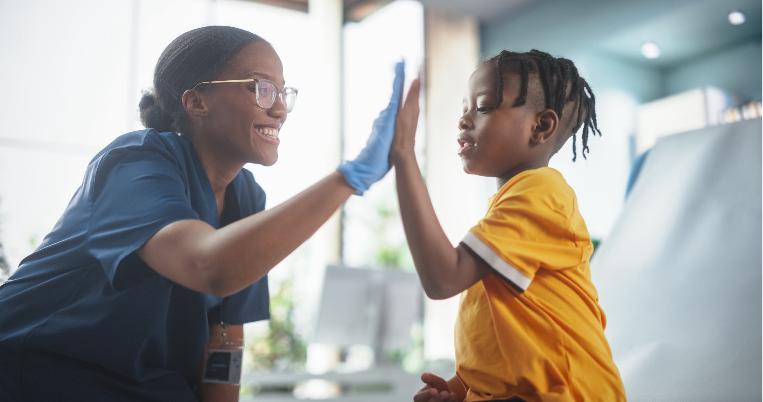 Smiling doctor giving a high five to her young patient